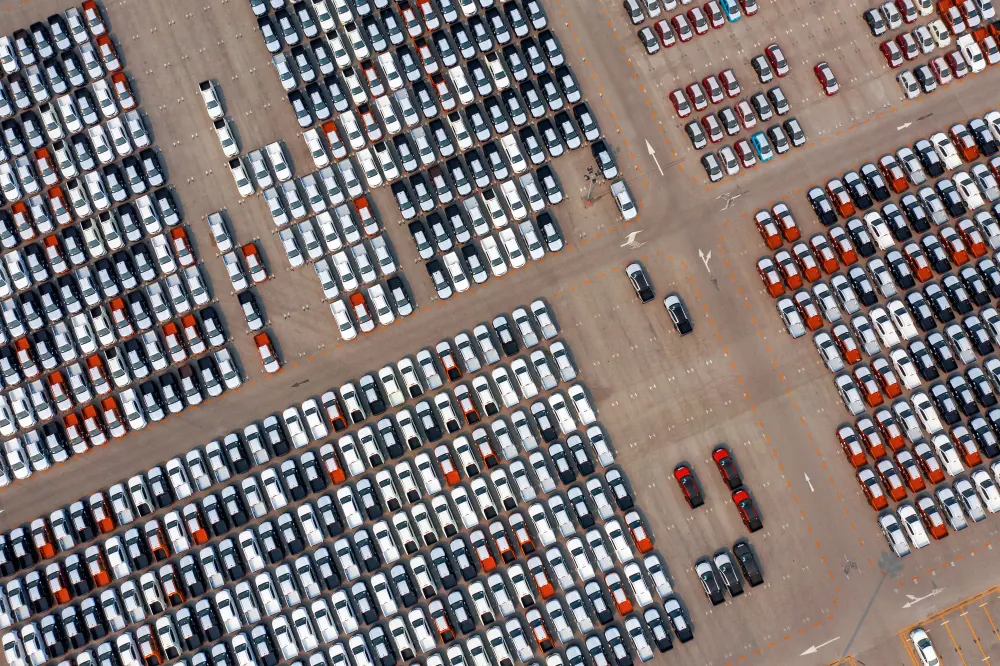 Aerial view of rows of new cars parked at a dealership storage lot